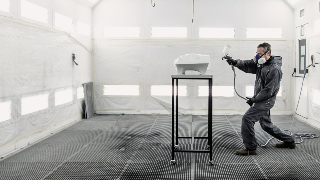 Man spraying paint on Toyota part in ED² studio paint booth